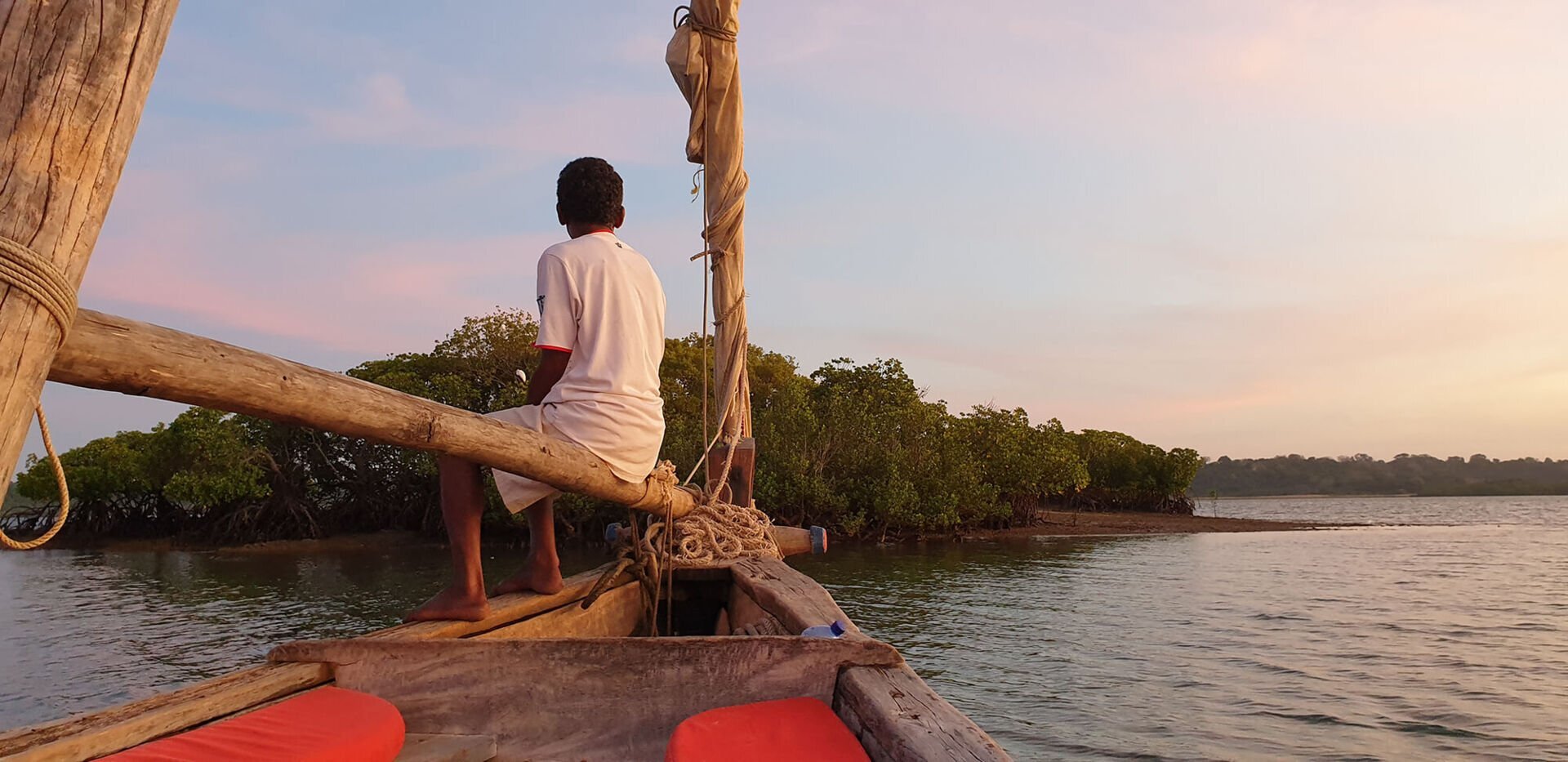 A guest watching the sunset from the bow of a dhow
