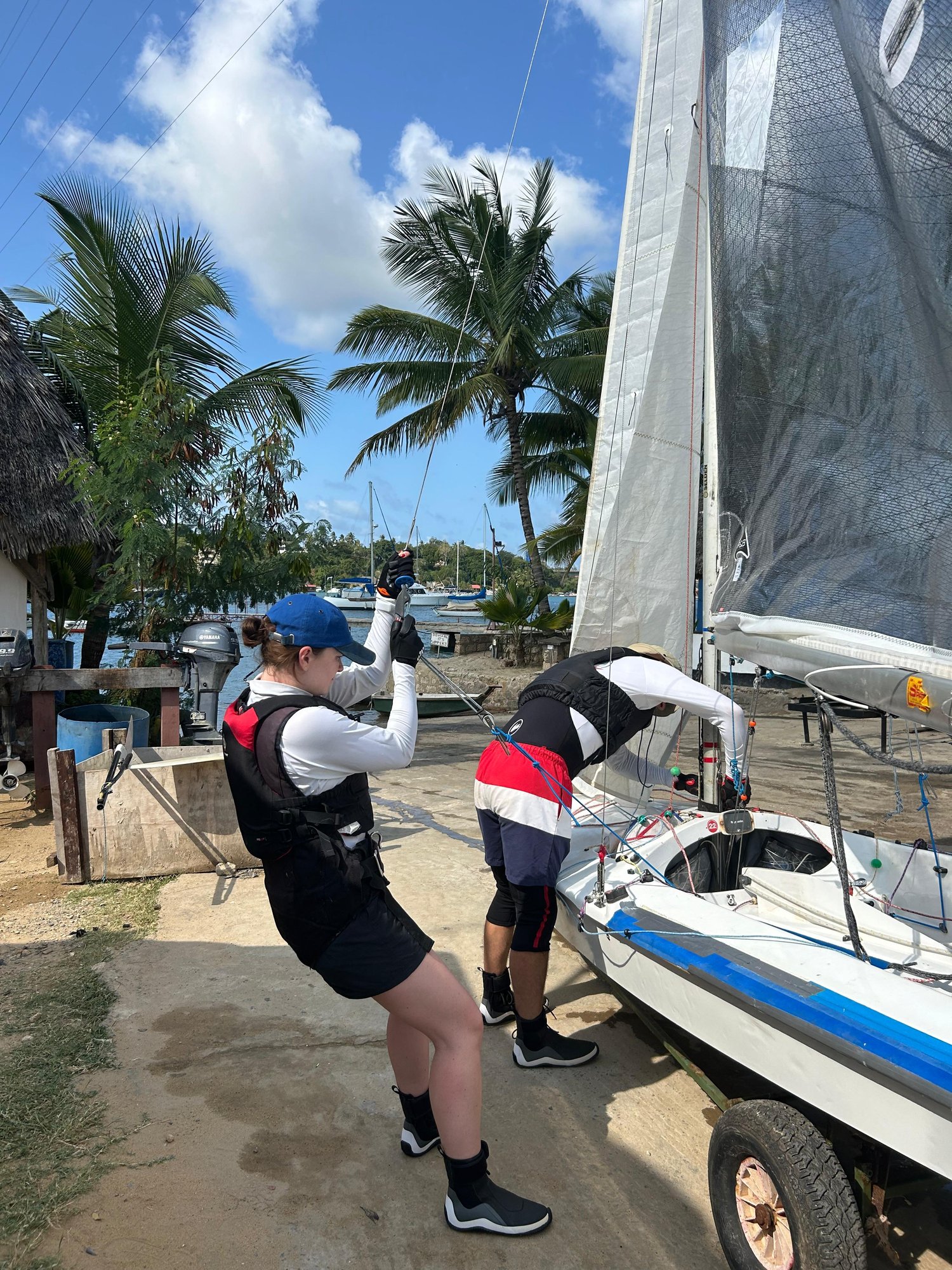 Crew rigging their Fireball in the boat park under the palms