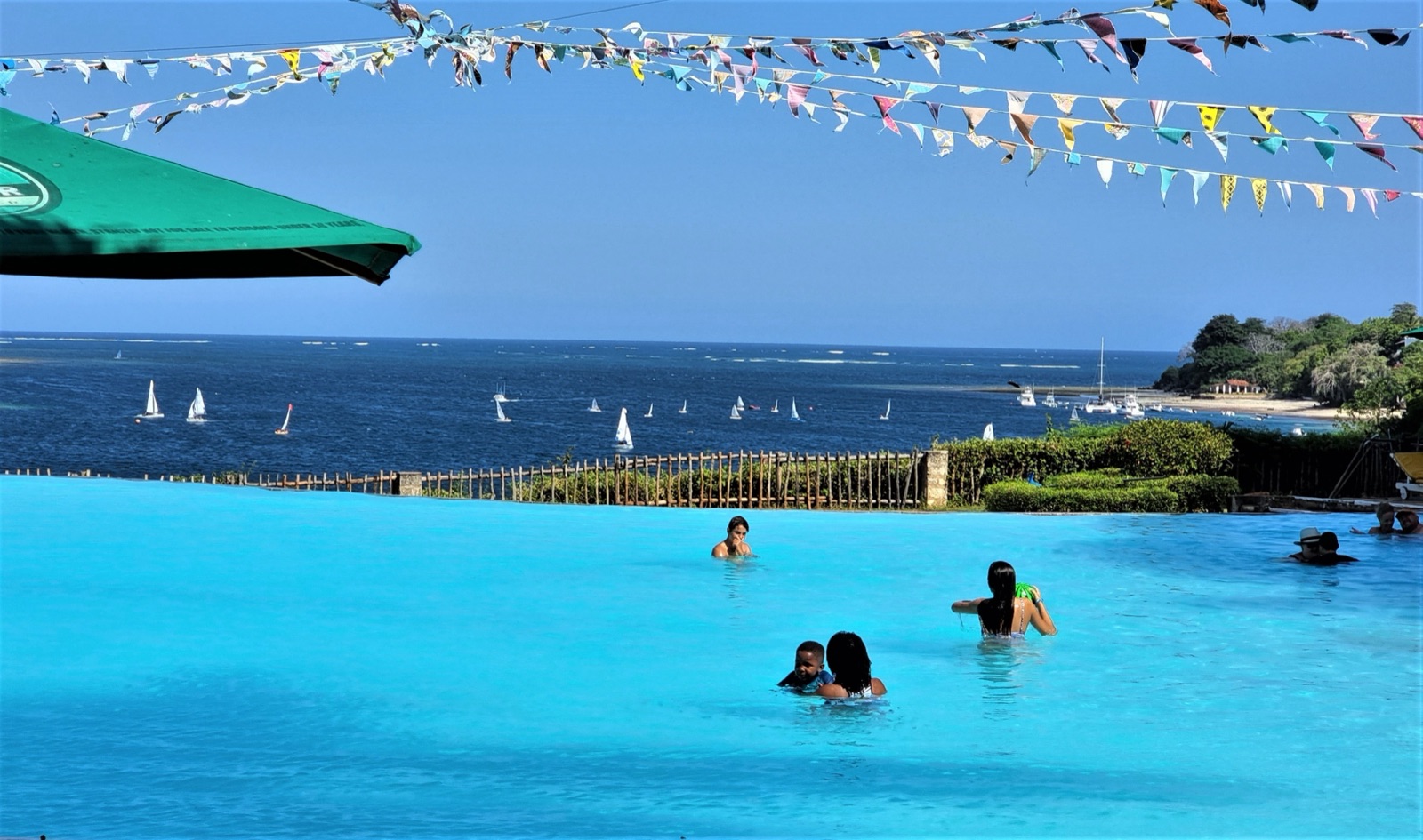 The infinity pool with sailing dinghies beyond